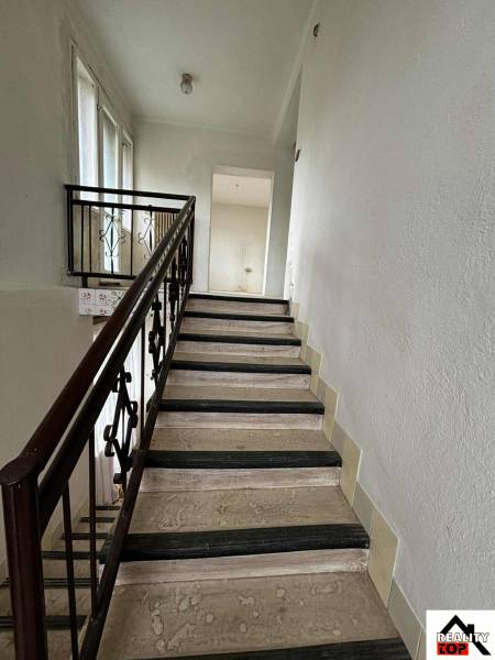 The staircase in the family house with a metal railing and windows provides natural light.
