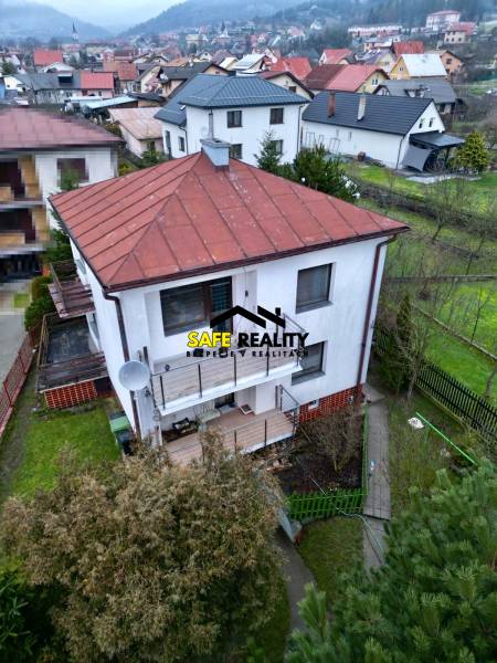 A family house in Nesluša with a sloped roof, a terrace, and a view of the surrounding houses.
