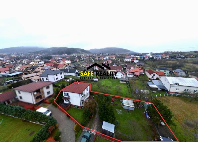 Aerial view of a family house in Nesluša, surrounded by a garden and surrounding buildings.