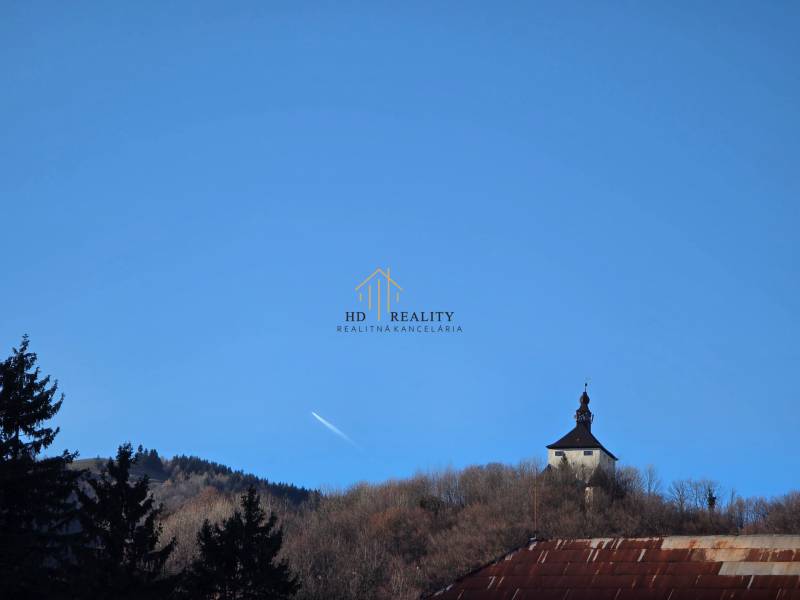 A tower in Banská Štiavnica with a blue sky and surrounded by trees.