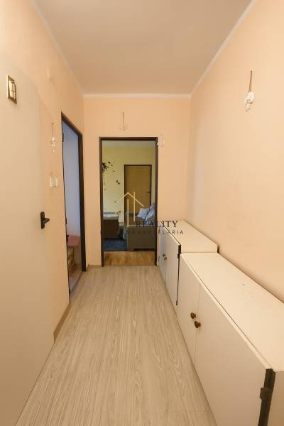 A hallway in a 3-room apartment with a wooden decor floor and white furniture.