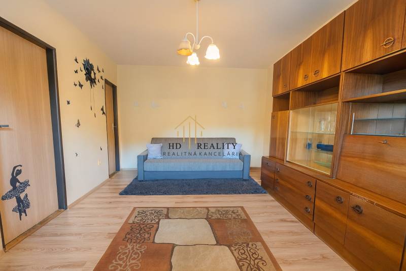 Living room in a three-room apartment with a wooden decor floor and a wooden living room wall unit.