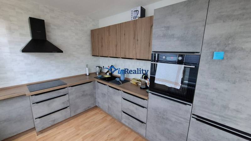 A kitchen in a 3-room apartment with a wooden decor floor and modern appliances.