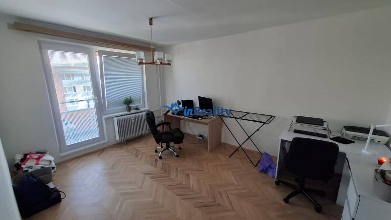 Home office in a 3-room apartment, wooden decor flooring, desks, chairs.