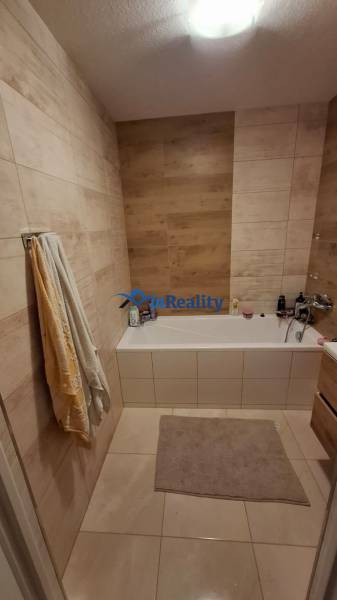 A bathroom in a 3-room apartment with a bathtub, tiled with wood decor.