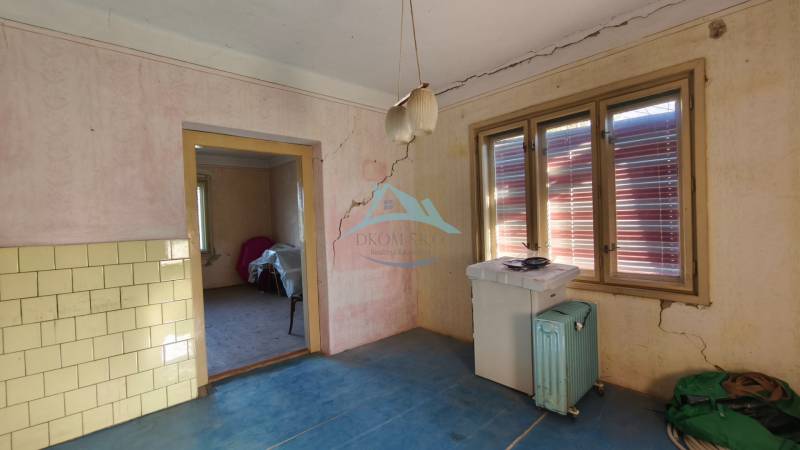 The interior of a family house with cracked walls, a blue floor, and an old radiator.