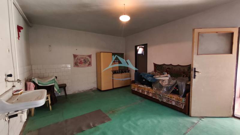A room in a family house with a sink, chairs, a sofa, and a wardrobe.