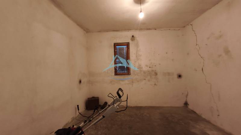 Basement with a window in a family house, walls with cracks and simple lighting.