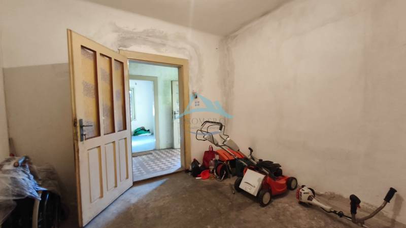 Interior of a family house with open doors, a lawnmower, and tools on the floor.
