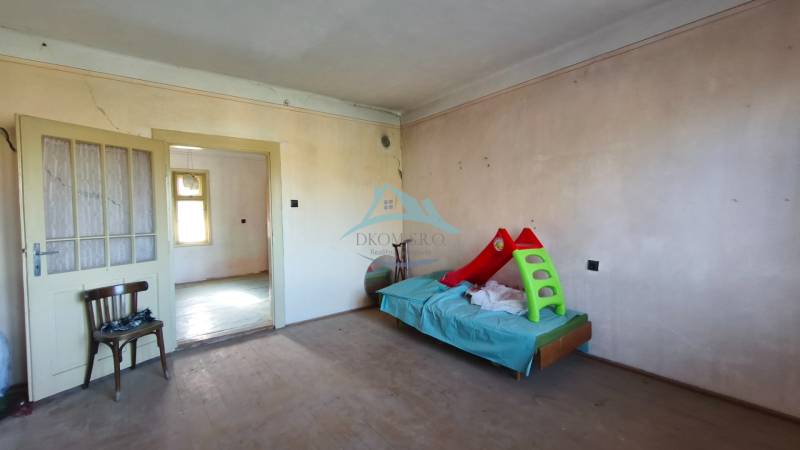 Interior of a family house with a bed, chair, and floor with wood decor.