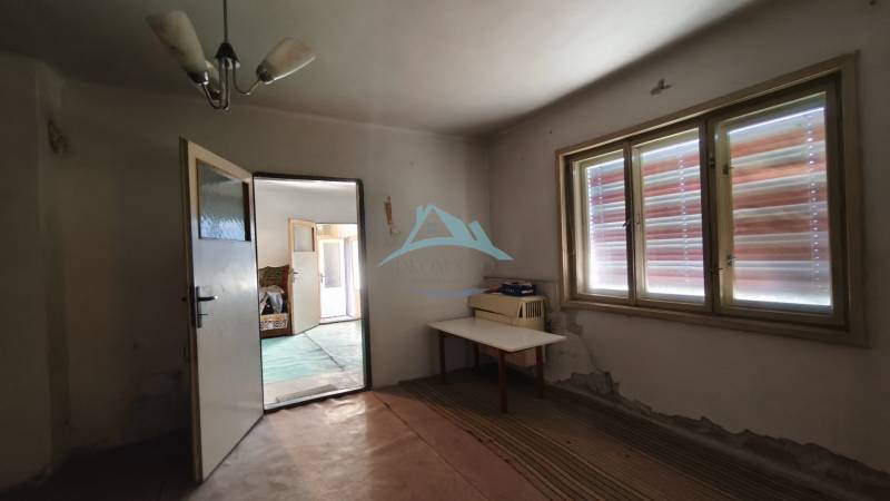 The interior of a room in a family house with open doors and a table by the window.