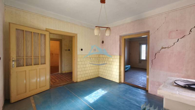 A room with a blue floor with a wooden decor, old doors, and cracks in the wall.
