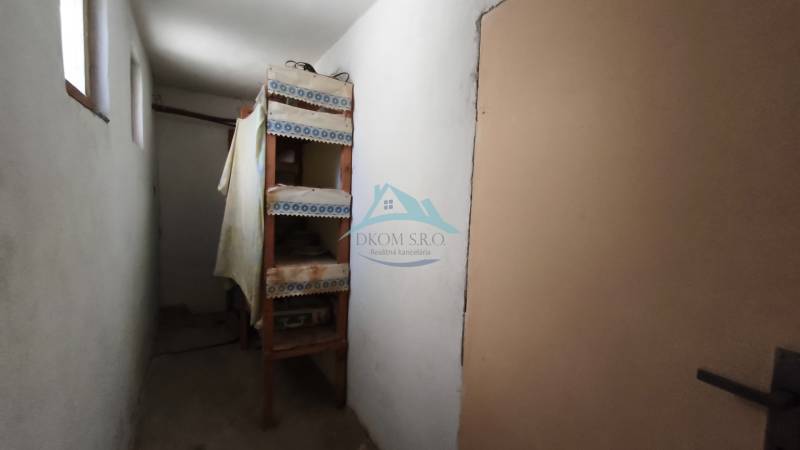 A narrow hallway with shelves in a family house, simple furnishings.
