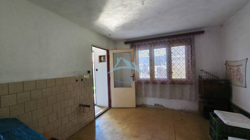 Interior of a family house with a window, curtain, and tiles on the wall.