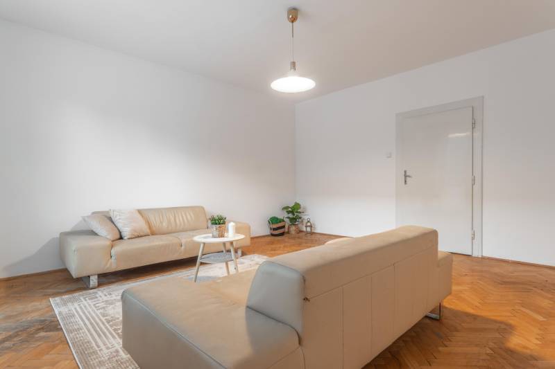 Living room in a 3-room apartment with sofas and wooden decor flooring.