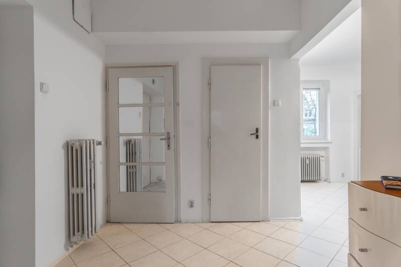 Interior of a 3-room apartment with white doors, a mirror, a radiator, and tiles.