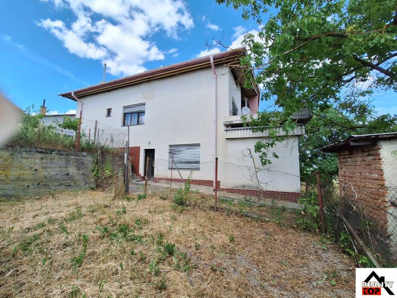 A family house in Nová Bašta with a garden and a partially cloudy sky.