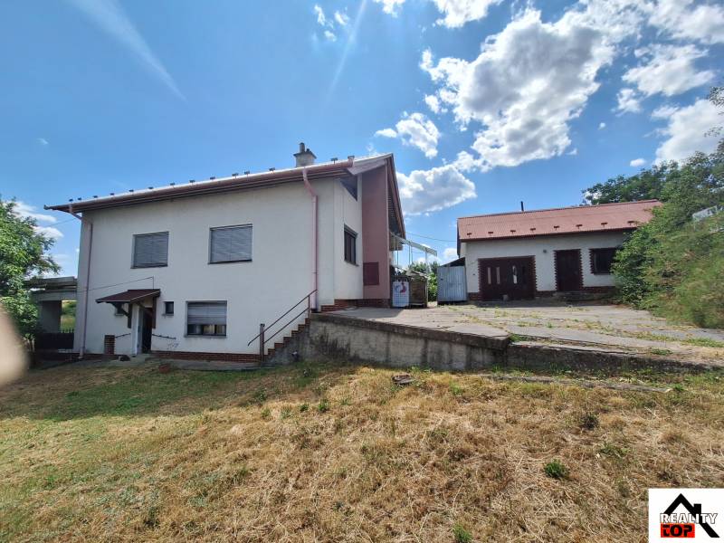 A family house in Nová Bašta with a grassy plot and an annex under the blue sky.