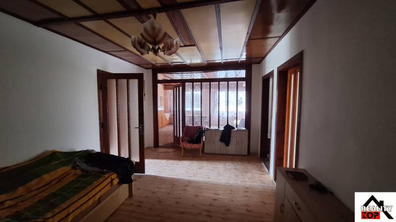 Interior of a family house with a wood-patterned floor, wooden doors, and older furniture.
