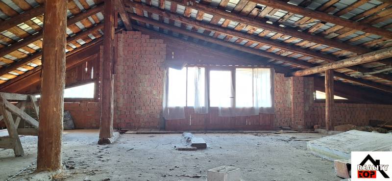 The attic of a family house with an exposed brick wall and wooden beams.