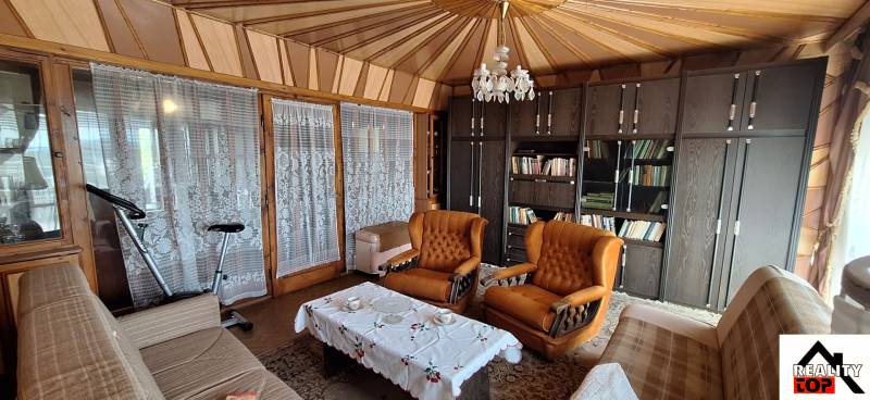 Living room with a library, orange armchairs, and a chandelier in a family house.
