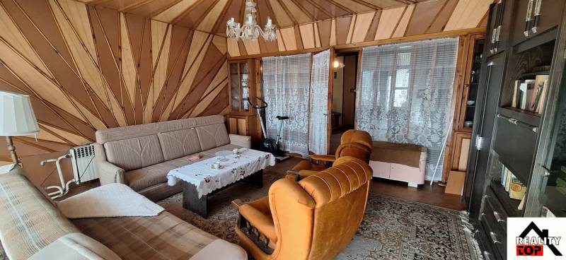 A living room with retro furniture, a chandelier, and patterned walls in a family house.