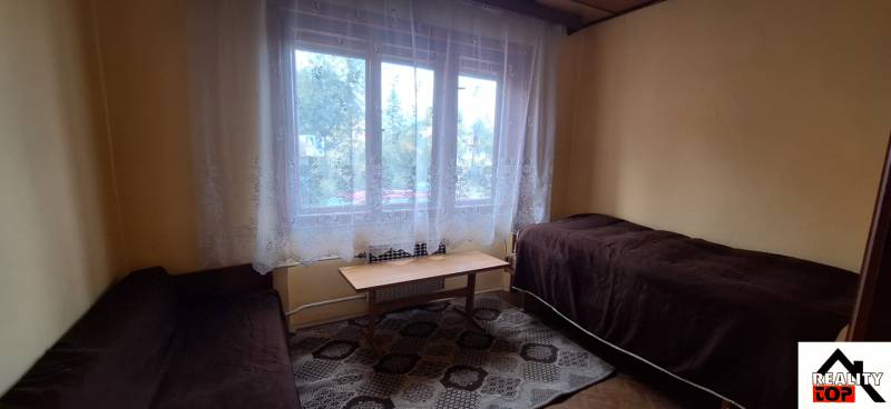 A room in a family house with two beds, a coffee table, and curtains.
