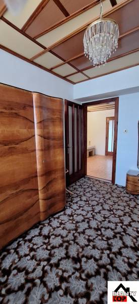 Family house with a floral patterned carpet, wooden doors, and a decorative chandelier.