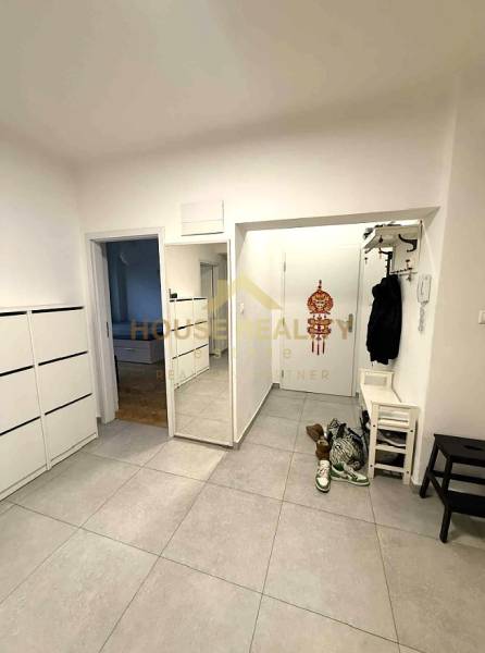 Hallway in a 4-room apartment with tiles, a shoe cabinet, and wall hooks.