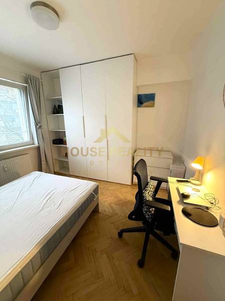 Bedroom in a 4-room apartment with a bed, wardrobe, desk, and floor with wood decor.