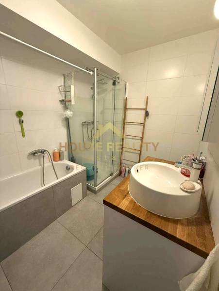 Bathroom in a 4-room apartment with a bathtub, shower, and a sink on a wooden countertop.