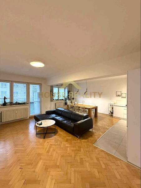 Living room of a 4-room apartment with a wooden decor floor and comfortable seating furniture.