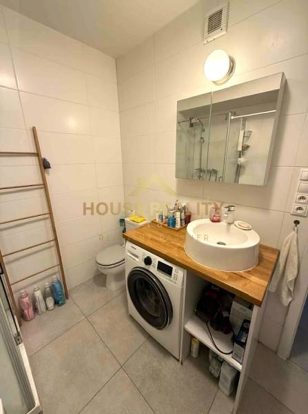 A bathroom with a washing machine and a sink in a 4-room apartment, next to the toilet and with a ladder radiator.