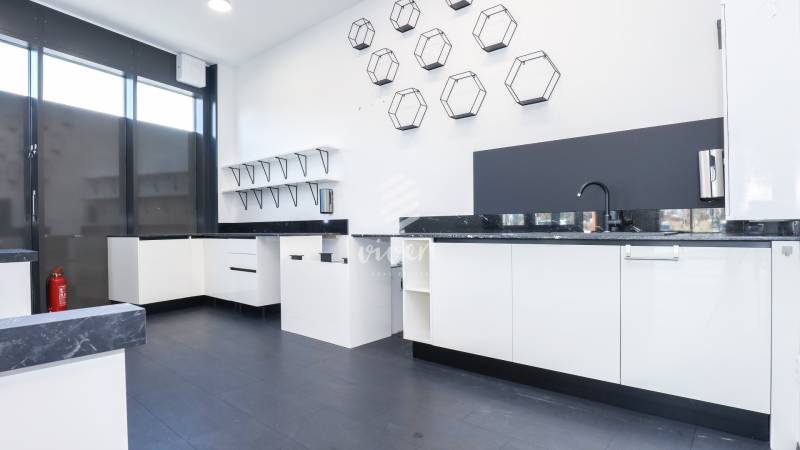 A kitchen in commercial premises with white cabinets, a black countertop, and unique decorations.