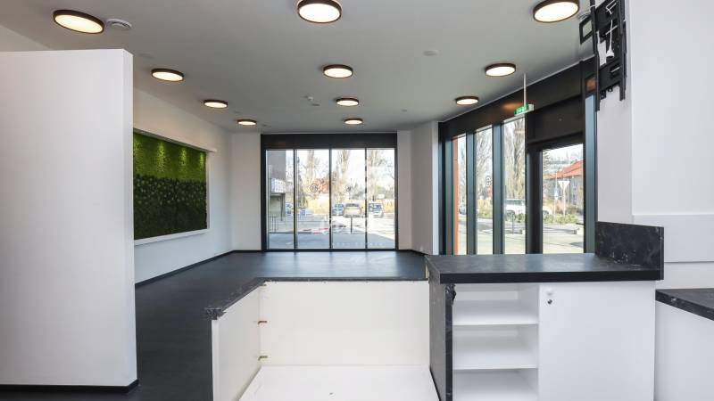Commercial spaces with large windows and a vertical garden, floor with wood decor.
