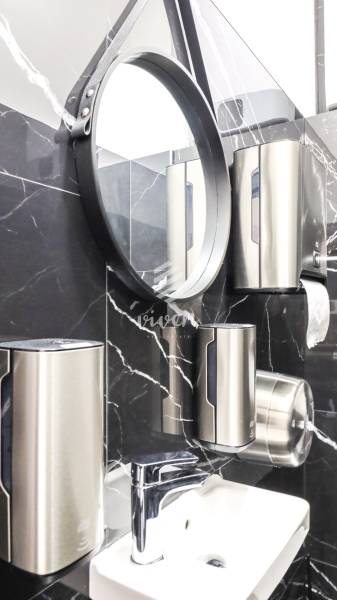Bathroom commercial spaces with a mirror, black marble, and stainless steel dispensers.