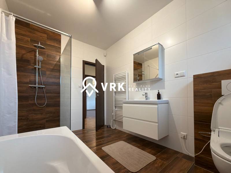 Bathroom with a shower, bathtub, and sanitary ware, floor with wooden decor in a family house.