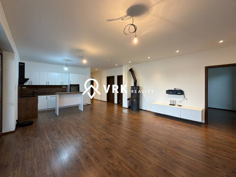 Open living room with kitchen in a family house, wooden decor flooring, white furniture.