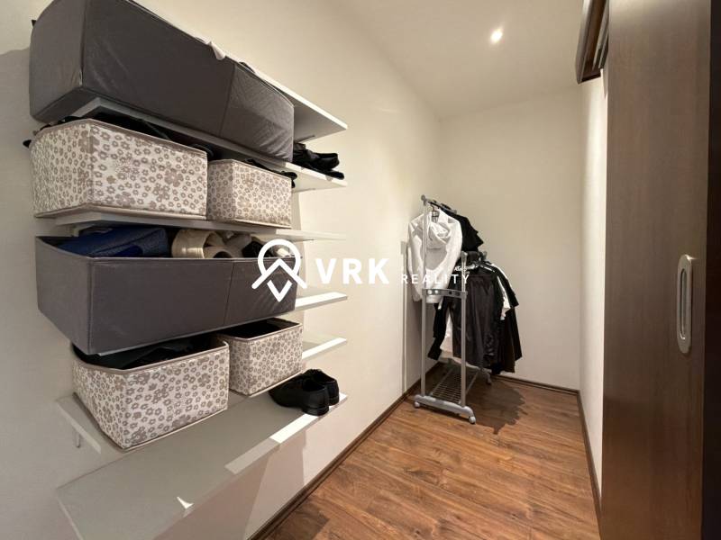 A wardrobe in a family house with a wooden decor floor, shelves with storage boxes.