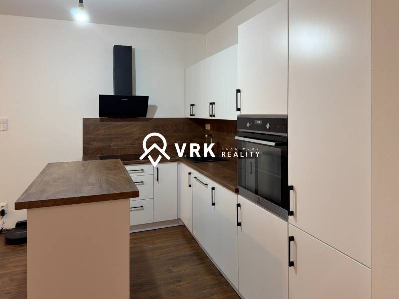 A kitchen in a family house with white cabinets and a wood-patterned floor.