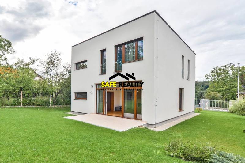 A family house in Žilina with a simple facade, lawn, and a terrace in the garden.