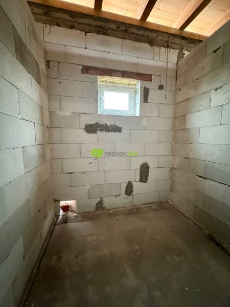 An unfinished room with a concrete floor and a window in a family house.