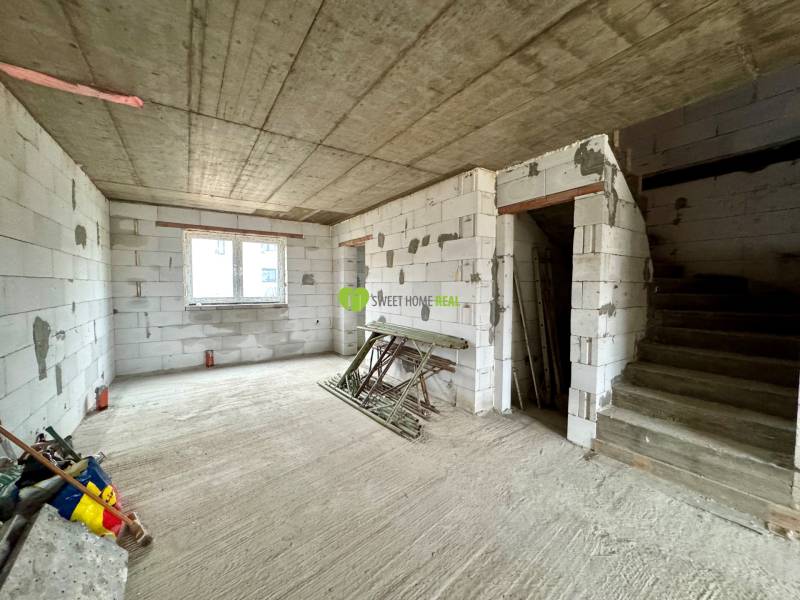 The interior of an unfinished family house with a concrete staircase and bare walls.
