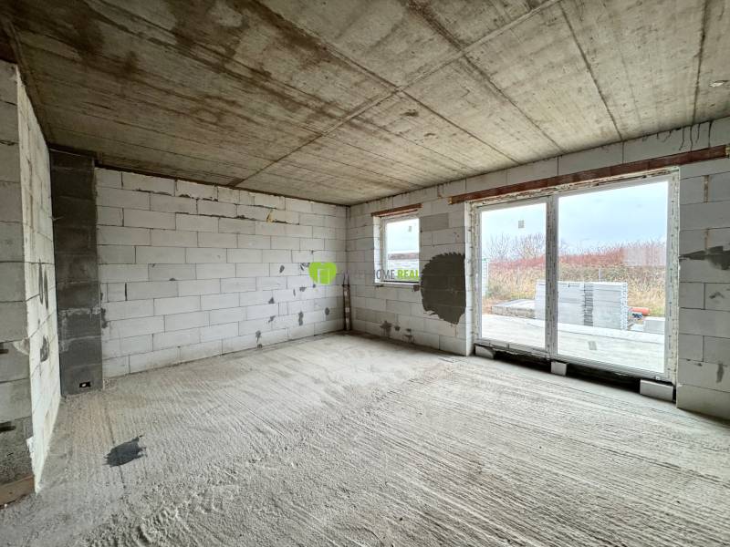 Unfinished space with concrete walls and large windows in a family house.