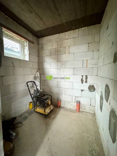 A building in a family house with an incomplete interior and an unfinished floor, with a window and machinery.