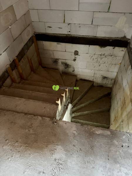 Concrete staircase in a family house with walls made of white blocks.