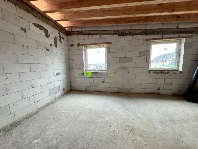The interior of a family house with unfinished walls and a ceiling made of wooden beams.