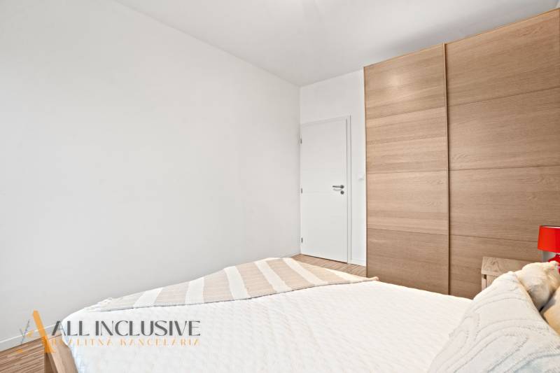 Bedroom in a 3-room apartment with a white wall, built-in wardrobe, and a red lamp.