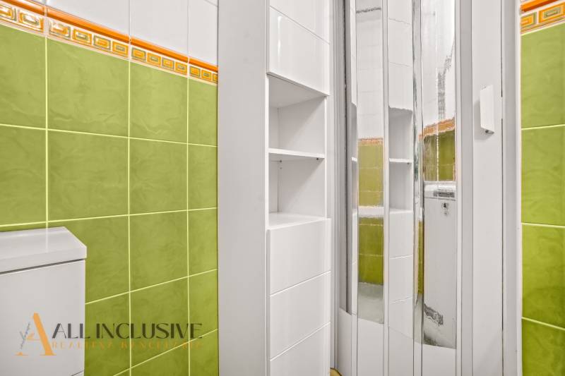 A bathroom with green tiles and a white cabinet in a 3-room apartment.
