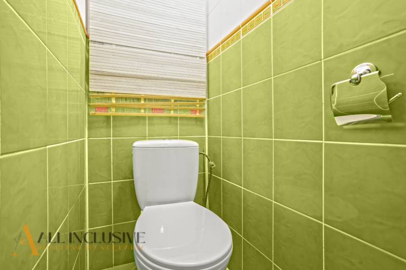 WC with a white toilet and green tiles in a 3-room apartment.